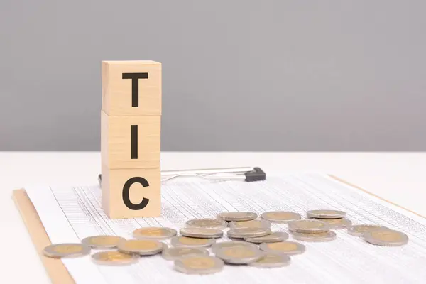 stock image wooden blocks on a brown background with the text TIC - an abbreviation for Tenancy In Common. strong business concept