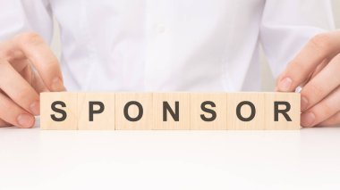 SpONSOR yazılı tahta küpleri tutan adam sponsorluk anlaşmasını ve desteği sembolize ediyor. Bir amaç, olay veya projenin desteklenmesi veya desteklenmesi için ortaklık, finansal destek ve aktif rol önerilir.