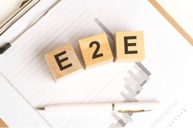 E2E sözcüğünün yer aldığı tahtadan küplerin finansal altyapısı tablo ve kalemle, iş konsepti