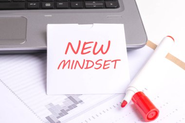 Beyaz arkaplan, dizüstü bilgisayar klavyesi, kırmızı kalem ve kağıt üzerinde NEW MINDSET içeren resim, yeni ve yenilikçi bir perspektif veya yaklaşımın benimsenmesini vurgulayarak, düşünce değişikliğini veya değişimi sembolize eder..