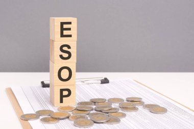 Tahta bloklardaki ESOP sözcüğü ve artan yığınla bozuk paralar. ESOP Personel Sahiplik Planı, çalışanların şirketlerin mülkiyetini paylaştığı güçlendirici bir kavramı temsil ediyor.