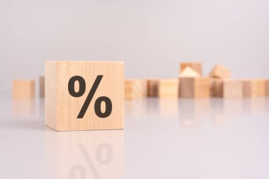 Tahta bir bloktaki yüzde işaretinin yakın plan çekimine karşı boş tahta küplerin arkaplanı finansal yüzdeler ve hesaplamalar kavramını taşır.