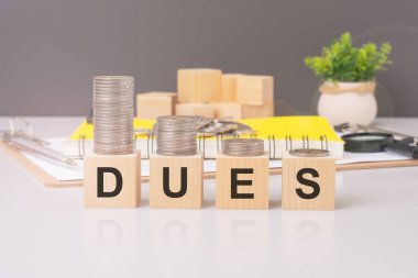 DUES 'i madeni paralarla heceleyen tahta blokların görüntüsü, mali işlemler, ücretler, giderler, ödemeler, fiyatlandırma, fiyatlar, fiyatlar, faturalar ve ücret öneriyor.