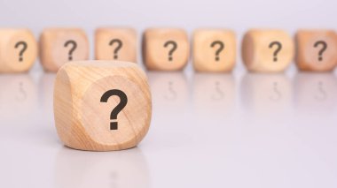 Ön planda, üzerinde soru işareti ve masa yüzeyinden yansıması olan bir tahta blok var. Arka planda, üzerinde soru işareti olan tahtadan bloklar var (odak dışı)).