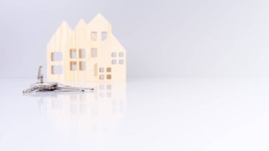 Evin anahtarları yakın planda, arka planda bulanık ev modelleri ve seçici odak noktası var. bir emlak konsepti taşır