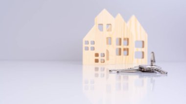 Evin anahtarları yakın planda, arka planda bulanık ev modelleri ve seçici odak noktası var. bir emlak konsepti taşır