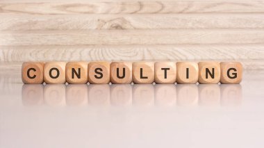 Gri arkaplandaki ahşap küplerin yazılışı profesyonel danışmanlık hizmetleri ve iş yardımını sembolize eder..