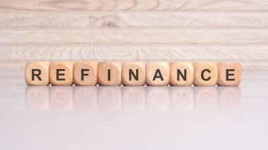 Gri arka planda 'REFINANCE' sözcüğünü oluşturan tahta bloklar, yeniden yapılanma veya yeni finansman terimleri elde etmekle ilgili bir mali kavramı işaret ediyor