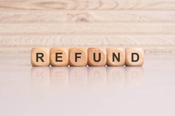 деревянные кубики со словом "возмещение", расположенные на глянцевой серой поверхности, с отражением и деревянным фоном