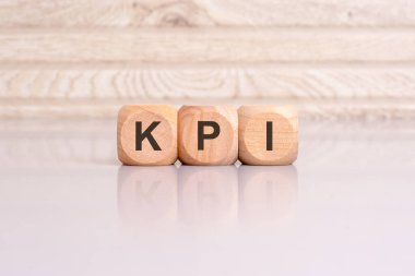 Tahta ışıklı arka planda KPI tabelası var. KPI - Anahtar Performans Göstergelerinin kısaltması