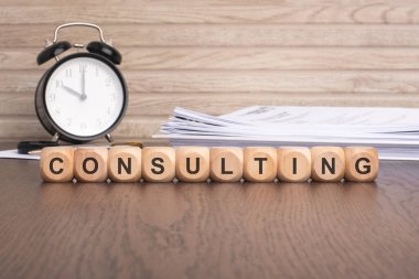 'CONSULTING' hecelenen ahşap küpler çeşitli alanlarda veya sektörlerde mesleki tavsiye, uzmanlık, rehberlik ve yardımı sembolize eder