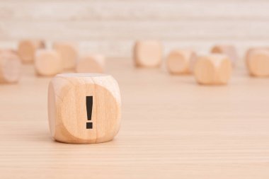 Üzerinde siyah ünlem işareti olan küçük tahta blok kahverengi bir arkaplan üzerinde vurgulama ve kopyalama alanı ile