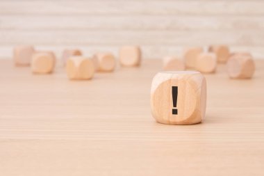 Üzerinde siyah ünlem işareti olan küçük tahta blok kahverengi bir arkaplan üzerinde vurgulama ve kopyalama alanı ile