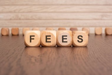 the text FEES is written on wooden blocks on a light background.