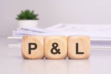 Ofis masasının üzerinde 'P ve L' harflerini yazan tahta küplerle arka planda P ve L harfleri var. Kâr ve zarar kelimesinin kısaltılmışı.