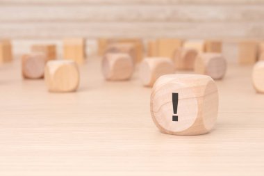 Üzerinde siyah ünlem işareti olan küçük tahta blok kahverengi bir arkaplan üzerinde vurgulama ve kopyalama alanı ile