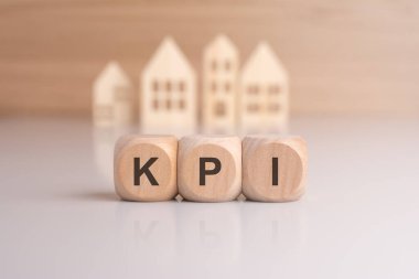 Bir sıra tahta blokta 'KPI - arka planda minyatür ev modelleriyle' Key Performans Göstergeleri 'nin kısaltması, emlak kredilerini temsil ediyor
