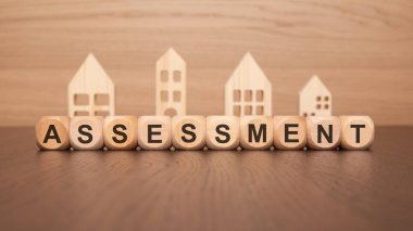 Ahşap bloklar 'ASSESSMENT' yazarken ev kesimleri, emlak anlaşmaları ve gayrimenkul fırsatları temsil