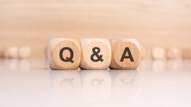 Masanın parlak yüzeyinde Q ve A harfleri olan üç tahta küp. Küplerdeki yazıtlar masanın yüzeyinden yansıyor. Soru-Cevap - Soru-Cevap 'ın kısaltması