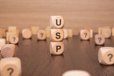 'USP' farklı derinlikteki ahşap küplerden imal edilmiştir ve ek küpler de etrafa saçılmıştır. Arka plan minimalist, dikkatleri tahta küplere odaklıyor..