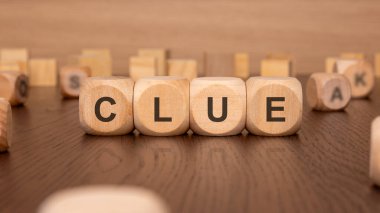 Kahverengi arkaplandaki 'CLUE' metniyle dört ahşap küpün görüntüsü sorun çözme, anlayış sağlama ve stratejik karar verme üzerine odaklanmış bir iş konseptini iletir