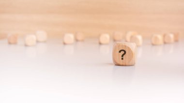 Üzerinde soru işareti olan tahta bir küp, ön plana belirgin bir şekilde yerleştirilmiş. Arka planda odağını kaybetmiş sayısız tahta küp derinlik ve merak duygusu yaratıyor..