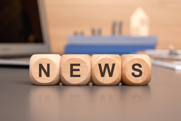 wooden blocks spelling NEWS on a desk symbolize news and media updates, representing communication and journalism