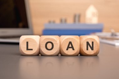 Masadaki ahşap bloklar finansal borçlanma, borç alma uygulamalarını ve kişisel ihtiyaçlar, iş yatırımları gibi çeşitli amaçlar için fon edinme kavramını sembolize ediyor