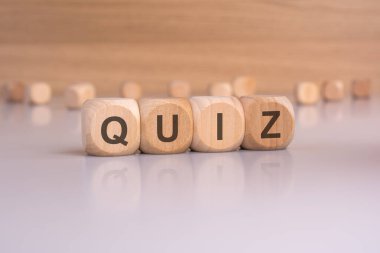 Bu fotoğraf 'QUIZ' hecelenen ahşap zar içerir, bilgi testi ve değerlendirme kavramını göstermek için mükemmeldir.