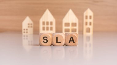 Tahta blokların hecelenmesi, yumuşak ve nazik bir arka plana karşı ahşap ev şekillerinin önüne yerleştirilir.