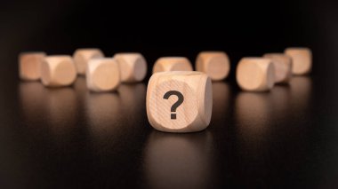 Soru işaretleriyle süslenmiş tahta küpler, doğuştan gelen merakımızı ve çeşitli fikirleri neşeli bir şekilde araştırmamızı temsil ediyor.