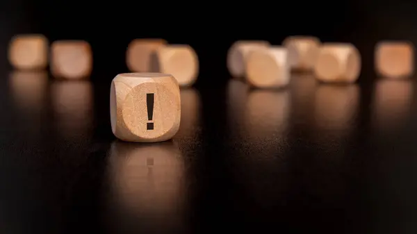 stock image a closeup of a carved wooden block with a prominent exclamation mark, symbolizing emphasis or alertness