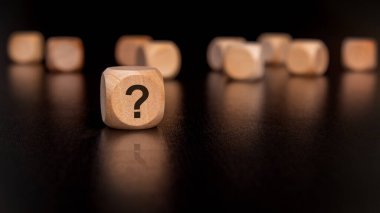 Soru işaretleriyle süslenmiş tahta küpler, doğuştan gelen merakımızı ve çeşitli fikirleri neşeli bir şekilde araştırmamızı temsil ediyor.