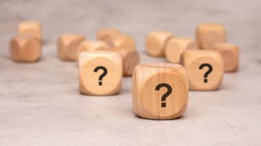 Hayattaki merak ve gizemi sembolize eden belirgin soru işaretlerini gösteren tahta bloklar.