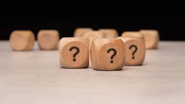 Wooden cubes, each prominently featuring question marks, symbolize inquiry, promoting deeper exploration and curiosity clipart