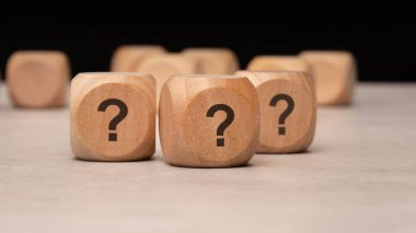 Tahta bloklar, hem merakı hem de belirsizliği simgeleyen canlı soru işaretleriyle süslenmiştir.