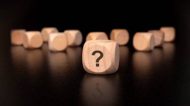 Soru işaretleriyle süslenmiş tahta küpler, doğuştan gelen merakımızı ve çeşitli fikirleri neşeli bir şekilde araştırmamızı temsil ediyor.