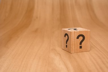 Soru işaretleriyle süslenmiş tahta bir blok gizem, merak, keşif ve bilinmeyen fikirleri somutlaştırır.