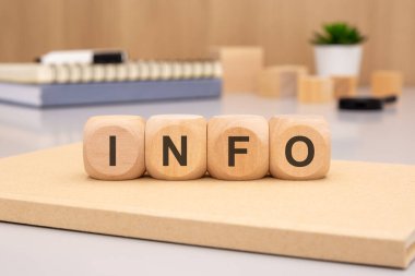INFO kelimesini heceleyen tahta bloklar, bilgi paylaşımını sembolize eden, temiz ve organize bir masada sergileniyor.