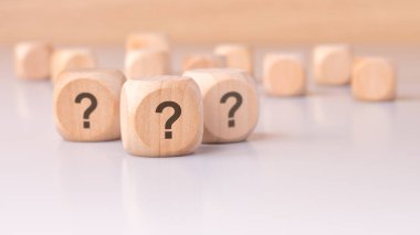 Tahta küpler soru işaretleriyle süslenmiş basit ama merak uyandıran bir ortamda merak ve gizemi temsil ediyor.