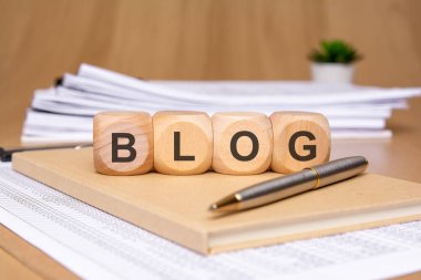 Tahta bloklar, bir kalem ve çeşitli kağıtlardan oluşan BLOG kelimesinin yer aldığı yaratıcı bir çalışma alanı