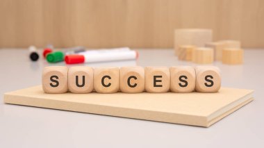 Yaratıcı bir çalışma alanı üzerinde SUCCESS sözcüğünü telaffuz eden ahşap blokları tasvir eden ilham verici bir görüntü.