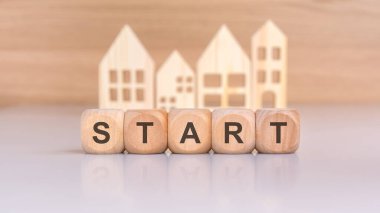 'START' ı ve minimalist ev şekillerini heceleyen tahta bloklar ile yeni başlangıçların görsel bir temsili..