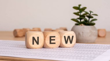 Yeşilliklerle çevrili, temiz bir çalışma alanında yeni başlangıçları sembolize eden tahta küpler.