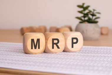 Tahta bloklar gururla MRP kısaltmasını sergiliyor. Minimalist ve şık bir yüzeye dikkatlice yerleştirilmiş..