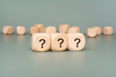 Beyaz arkaplanda görünen açıda üç sıra tahta küp soru işaretleri