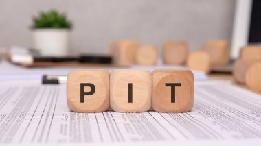 Bu tahta bloklar kişisel gelir vergisinin kısaltması olan P, I ve T. PIT harflerini yaratıcı bir şekilde sergiliyor.