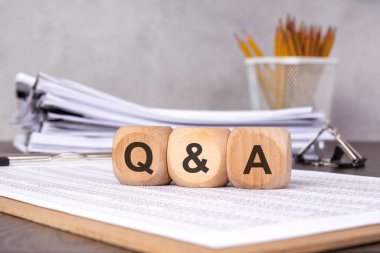 Ofis malzemeleriyle birlikte 'Q ve A' yazılı ahşap bloklar. müşteri desteği, iş iletişimi, şirket toplantıları, FAQ 'lar ve profesyonel tartışmaları temsil eder