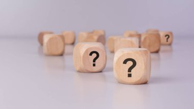 Yansıtıcı yüzeyinde yazılı soru işaretleri olan dağınık ahşap küpler. Şüphe konsepti, seçimler, risk, bilinmeyen gelecek, iş kararları, problem çözme, merak, beyin fırtınası ve stratejik düşünme.