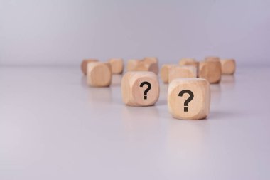 Yansıtıcı yüzeyinde yazılı soru işaretleri olan dağınık ahşap küpler. Şüphe konsepti, seçimler, risk, bilinmeyen gelecek, iş kararları, problem çözme, merak, beyin fırtınası ve stratejik düşünme.